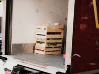 A wooden crate with fresh vegetables loaded inside a delivery truck, ready for transportation.