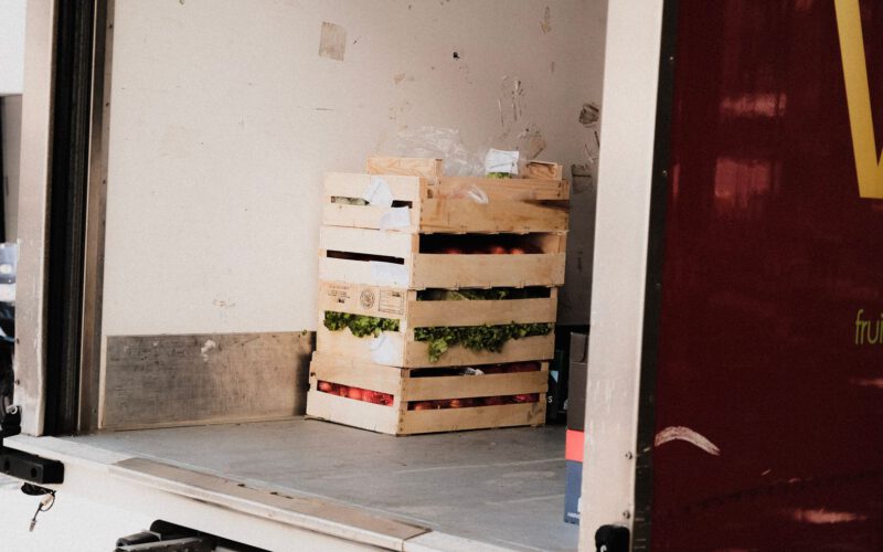 A wooden crate with fresh vegetables loaded inside a delivery truck, ready for transportation.
